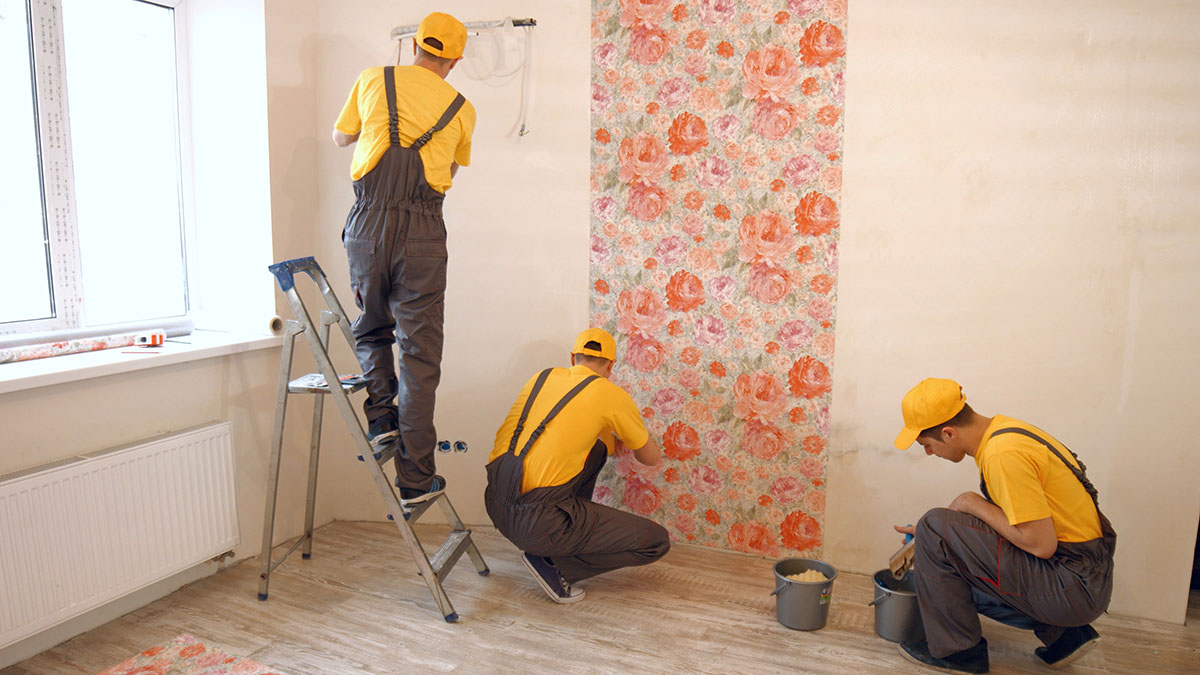 Brigade of builders hang wallpaper in the apartment. Contractor repairing apartments. Home improvement concept.